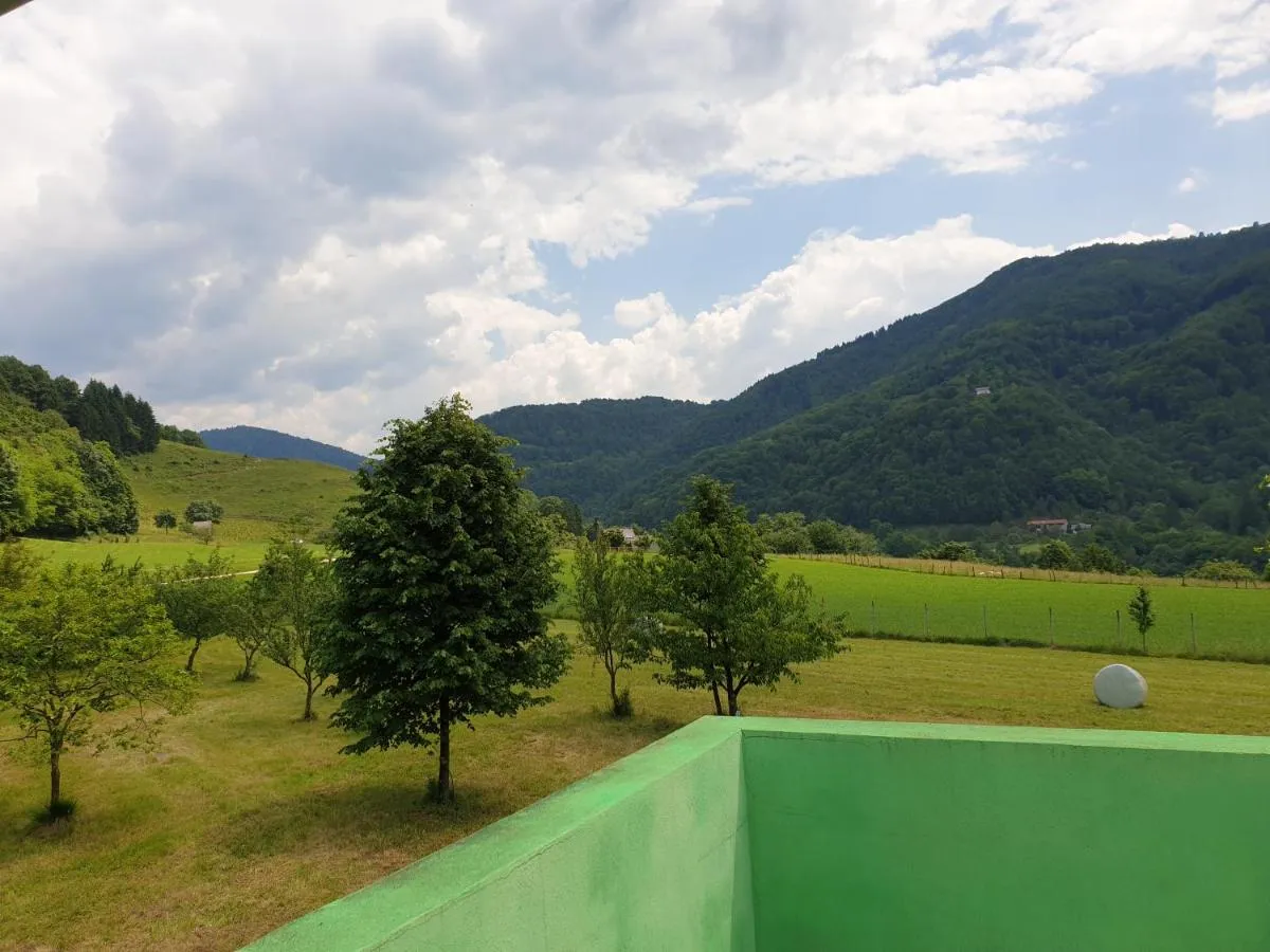 Razgled s terase na sadovnjak, travnike in gozdnate hribe nad Soško dolino