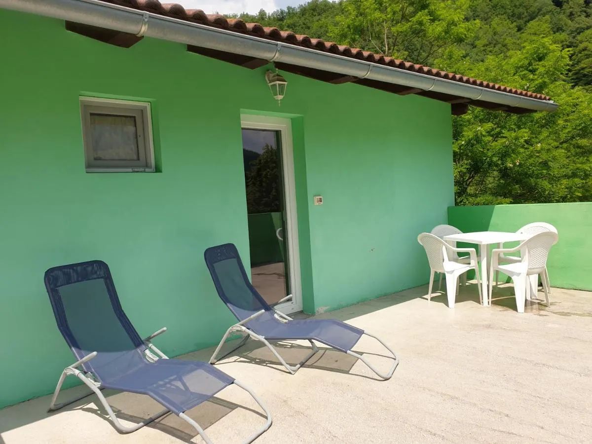 Terasa pred mintno zeleno steno apartmaja z dvema ležalnikoma, mizo in stoli